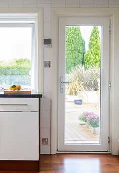 a kitchen with white cabinets and black counter tops next to a door that leads to an outside patio