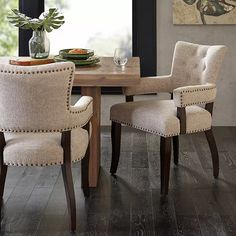 a dining room table with two chairs and a vase on top of the wooden table