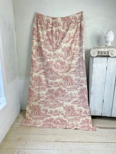 a pink and white blanket sitting on top of a wooden floor next to a window