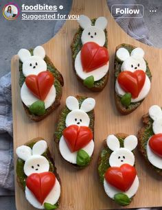 some food is on a wooden board with white frosting and red tomatoes in the shape of rabbits