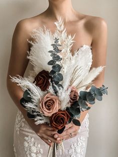 a woman in a white dress holding a bouquet with flowers and feathers on her chest