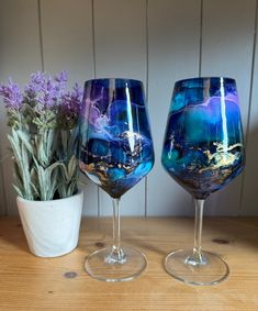 two wine glasses sitting on top of a table next to a vase filled with flowers