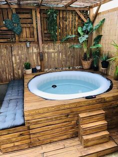 an outdoor hot tub with steps leading up to it and potted plants on the side