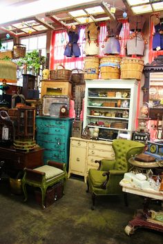 a room filled with lots of furniture and antiques in front of a large window that is open