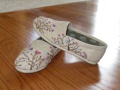 two pairs of white shoes sitting on top of a wooden floor