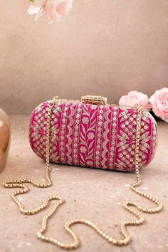 "Put together the perfect wedding look with our Mirai Embroidered clutch. This bag effortlessly delivers the Indian festive look. The luxe gold embroidery is a visual delight to the eyes. The gold tassels and the gold scallop lace add on to the grandeur of the bag. It's the perfect accessory for the bride to be who will be the center of attention.   Color: Pink with gold embroidery Dimensions (LxB): 8\"x4\" Handle length: 47\" Handle drop: 23\" Material: Embroidered poly silk, suede lining, golden metal clutch frame, golden metal sling. Features: metal lock closure, detachable metal sling." Luxury Gold Embroidered Clutch For Wedding, Luxury Wedding Clutch With Gold Embroidery, Designer Gold Shoulder Bag As A Gift, Designer Gold Clutch For Festive Occasions, Designer Gold Shoulder Bag As Gift, Designer Festive Gold Clutch, Gold Evening Bag With Handwork For Reception, Gold Rectangular Clutch With Zari Work, Designer Gold Evening Bag For Festive Occasions