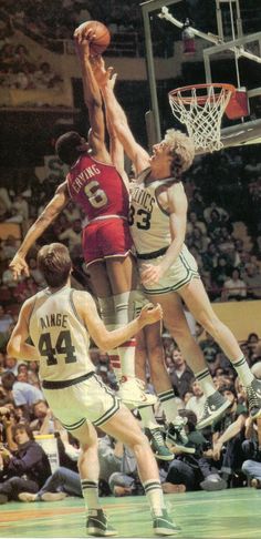 a group of men playing basketball against each other in front of an arena full of people