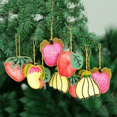 an ornament hanging from a christmas tree decorated with apples and acorns