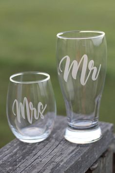 two clear wine glasses with the word mr and mrs on them sitting on a wooden table