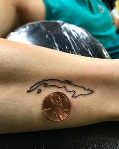 a penny sitting on top of a table next to a woman's arm with a tattoo