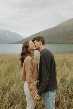 a man and woman standing next to each other in tall grass