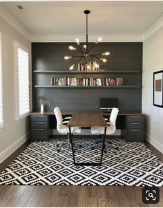 a room with a table, chairs and bookshelves on the wall above it