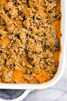 a casserole dish filled with meat and sauce on a marble counter top, ready to be eaten