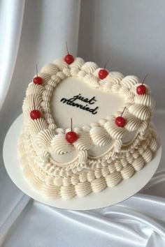 a heart shaped cake with cherries on the top is sitting on a white plate