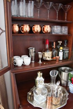 an old china cabinet with wine glasses, cups and other condiments on it