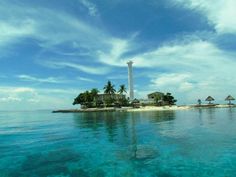 an island in the middle of the ocean with palm trees and huts on it's sides