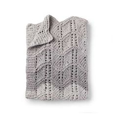 a gray knitted blanket sitting on top of a white wall