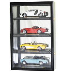 four cars are on display in a glass case with black frame and white wall behind them