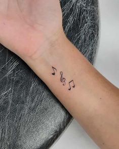 a woman's wrist with musical notes tattooed on the left side of her arm