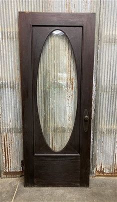 an old wooden door with glass on the front and side panels, in front of a corrugated wall