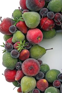 a wreath made out of apples, pears and grapes on a white background with frosting