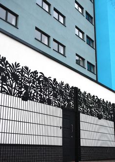 a black and white fence is next to a tall building with blue sky in the background