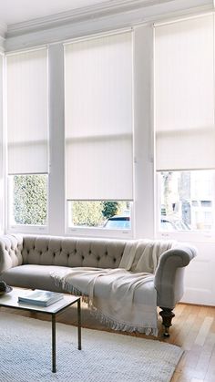 a living room filled with furniture and windows covered in white blinds on top of them