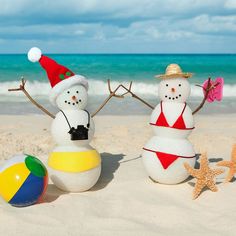 two snowmen in bathing suits and hats on the beach next to a starfish