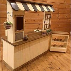 a small wooden counter with a window and potted plants on it in front of a wood paneled wall