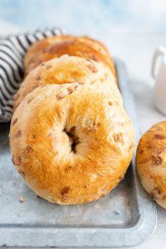 three bagels sitting on top of a metal tray next to a cup and saucer