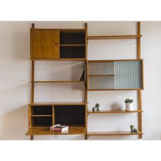 a book shelf with books and other items on it in front of a white wall