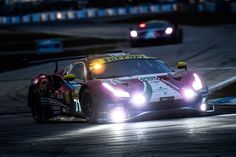 a racing car driving on a race track at night with lights on it's head