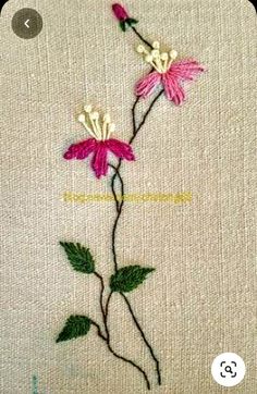 a close up of a flower on a piece of cloth with stitching in it