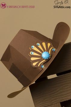 a brown paper hat with blue beads and a peacock on it's brim