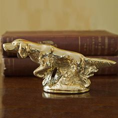 a golden dog figurine sitting on top of a wooden table next to some books