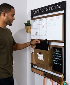 a man standing in front of a bulletin board with sticky notes and plants on it