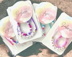 four personalized bracelets with name tags on them sitting in front of a rock