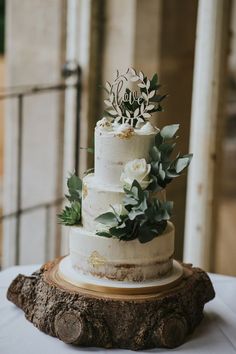 a white wedding cake with greenery on top