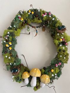 a wreath made out of moss with mushrooms and other things around it on the wall