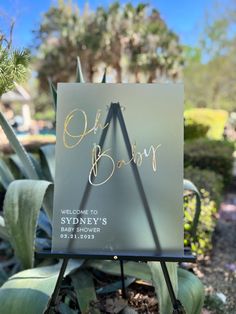 a sign that is sitting on top of a plant in front of some plants and bushes