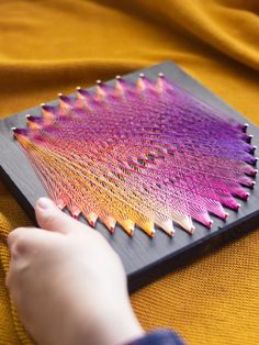 a person holding a piece of string art