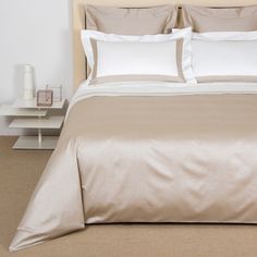 a bed with white pillows and beige sheets