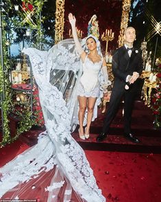 the bride and groom are walking down the red carpet at their wedding ceremony in front of an elaborately decorated stage