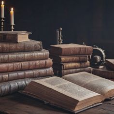 an open book sitting on top of a wooden table next to two candles and books