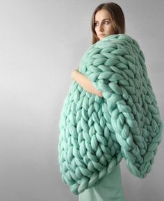 a woman is holding a large chunky blanket in front of her face and looking at the camera