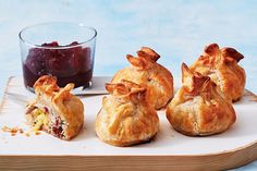 several pastries on a tray with a bowl of fruit in the background