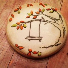 a painted rock sitting on top of a wooden floor next to a tree with leaves