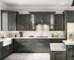 a kitchen with gray cabinets and marble counter tops