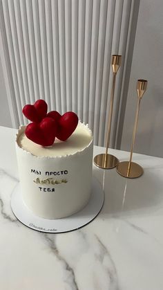 a white cake with red hearts on top and two gold spoons next to it