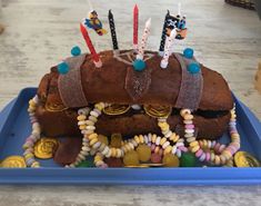 a birthday cake with candles on top of it sitting in a blue tray filled with candy